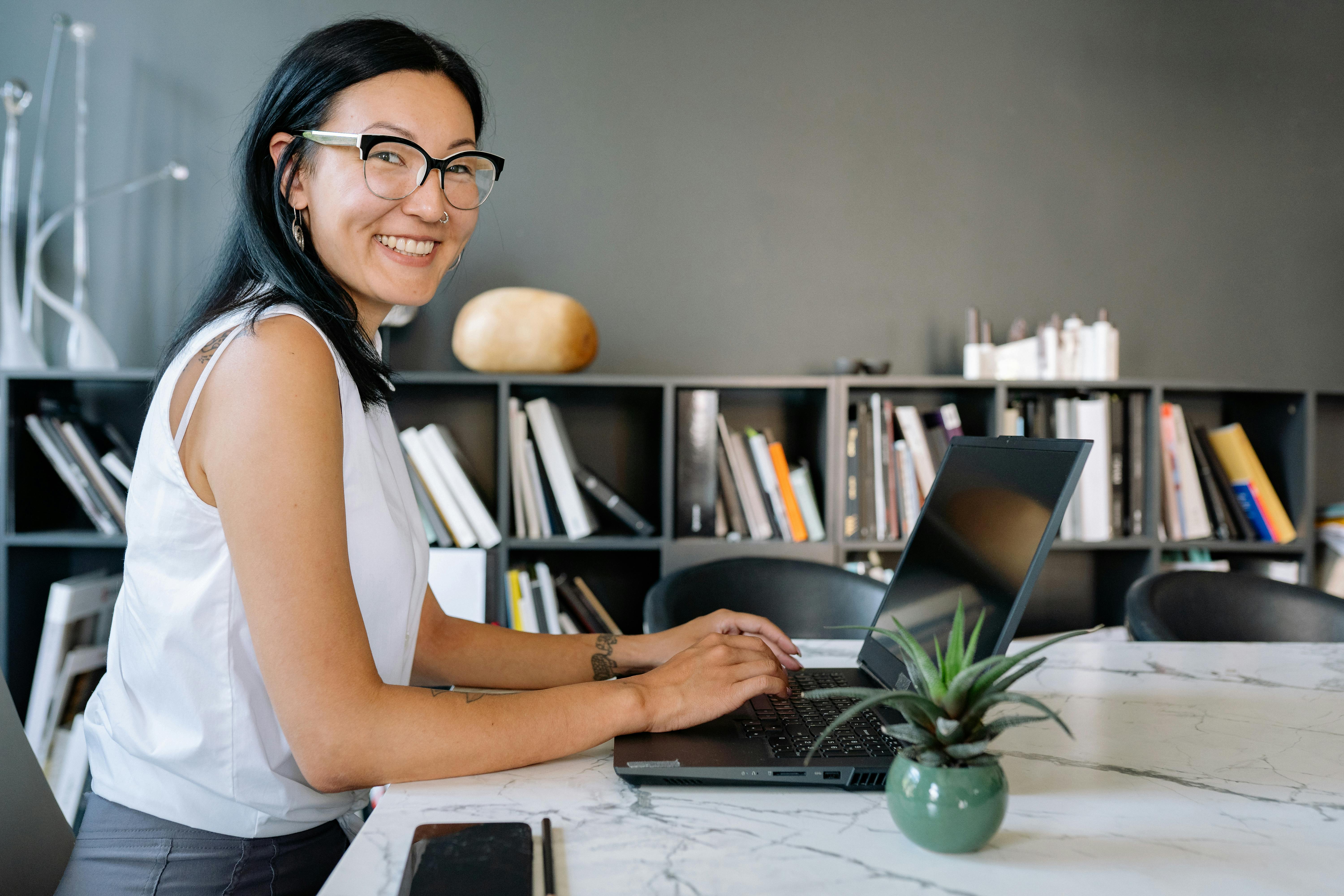 Smiling Asian woman working on laptop